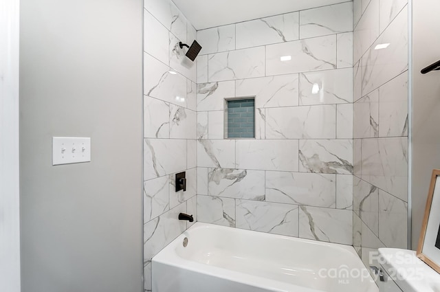 bathroom featuring toilet and tiled shower / bath