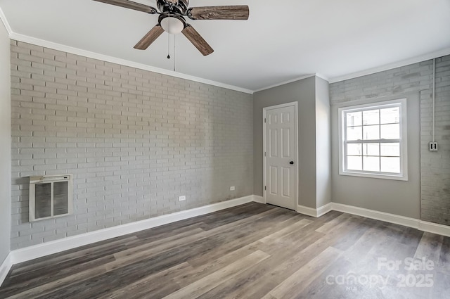 spare room featuring ceiling fan, wood-type flooring, brick wall, and ornamental molding