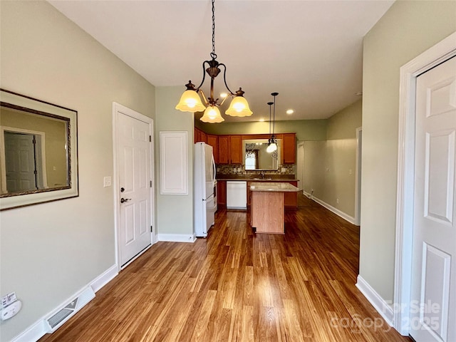 kitchen featuring a center island, white appliances, decorative backsplash, dark wood-type flooring, and pendant lighting