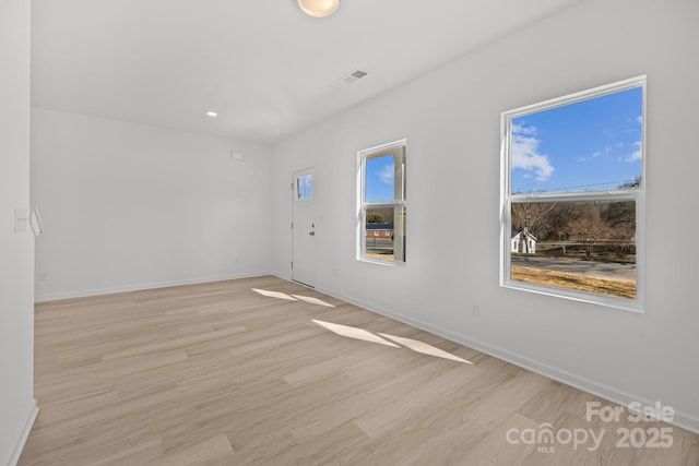 unfurnished room featuring light wood-type flooring, baseboards, and visible vents