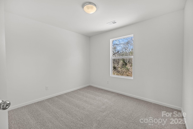 carpeted empty room featuring visible vents and baseboards