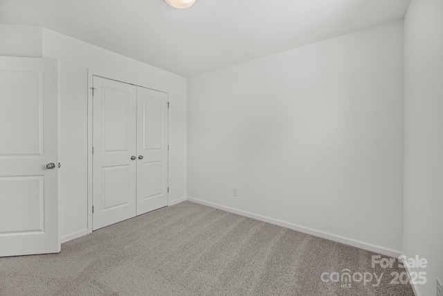 unfurnished bedroom featuring carpet floors, baseboards, and a closet