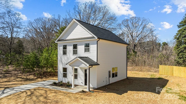 view of side of property with a shingled roof and fence