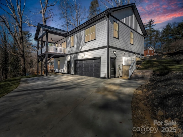 property exterior at dusk with a garage and a balcony