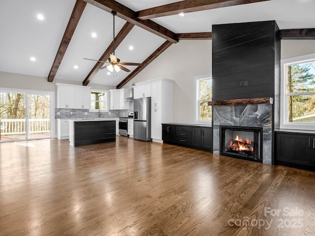 unfurnished living room with a healthy amount of sunlight, a high end fireplace, and high vaulted ceiling