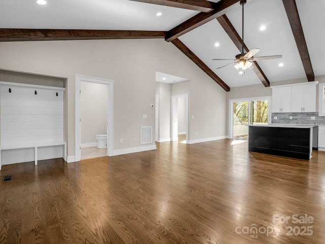 unfurnished living room featuring beam ceiling, ceiling fan, dark hardwood / wood-style floors, and high vaulted ceiling