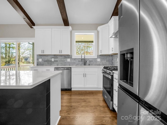 kitchen featuring tasteful backsplash, beam ceiling, stainless steel appliances, and white cabinets