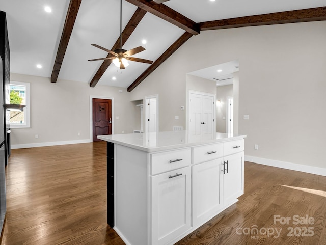 kitchen featuring beamed ceiling, white cabinetry, dark hardwood / wood-style flooring, a center island, and ceiling fan