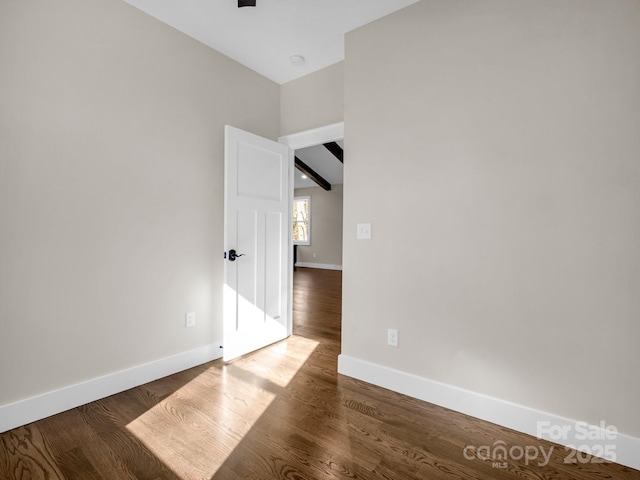 spare room featuring dark hardwood / wood-style floors and lofted ceiling with beams