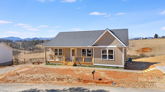 view of front facade featuring a porch, crawl space, a shingled roof, and a mountain view