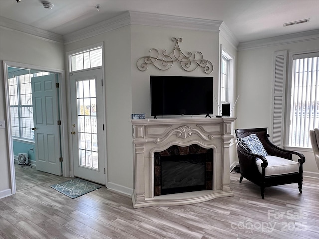 entrance foyer with crown molding, a high end fireplace, and light hardwood / wood-style floors