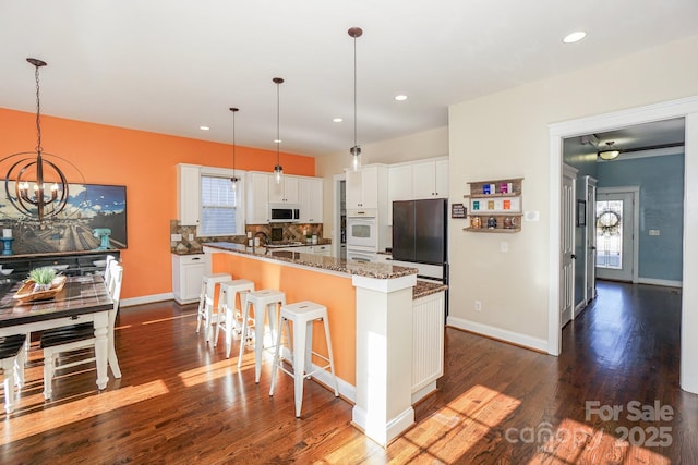 kitchen with pendant lighting, white cabinetry, dark stone countertops, dark hardwood / wood-style flooring, and fridge