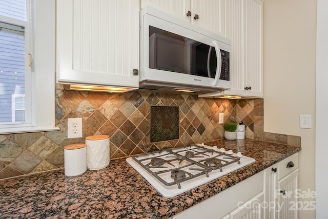 kitchen with tasteful backsplash, white cabinetry, white appliances, and dark stone counters