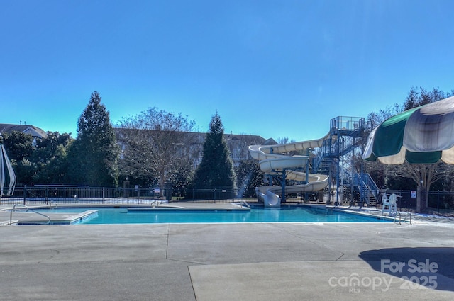 pool with a water slide, fence, and stairway