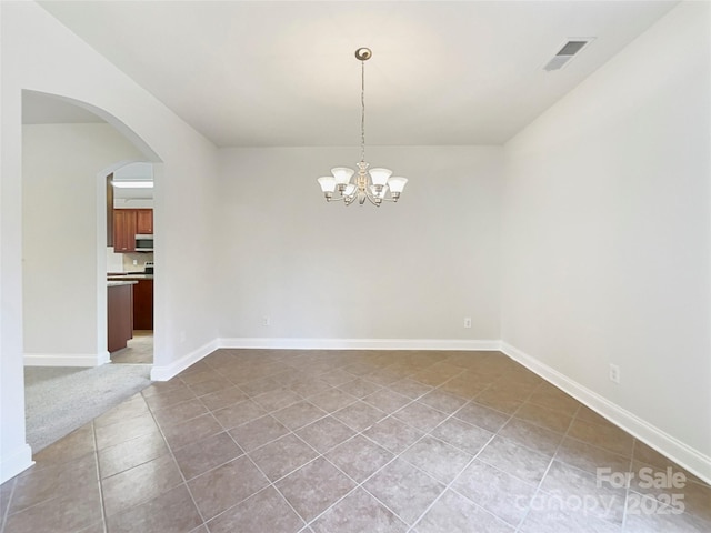 tiled empty room with a chandelier