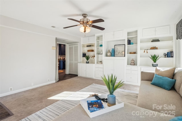 carpeted living room with built in shelves and ceiling fan