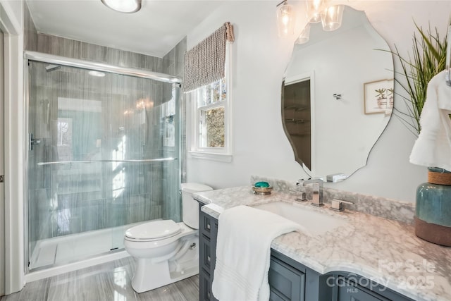 bathroom with vanity, a shower with door, and toilet