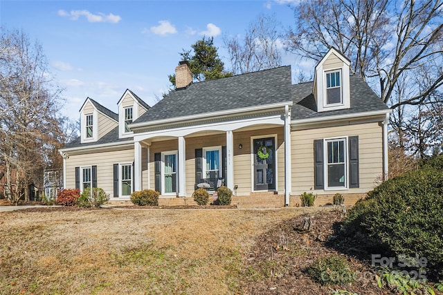 new england style home with covered porch and a front lawn