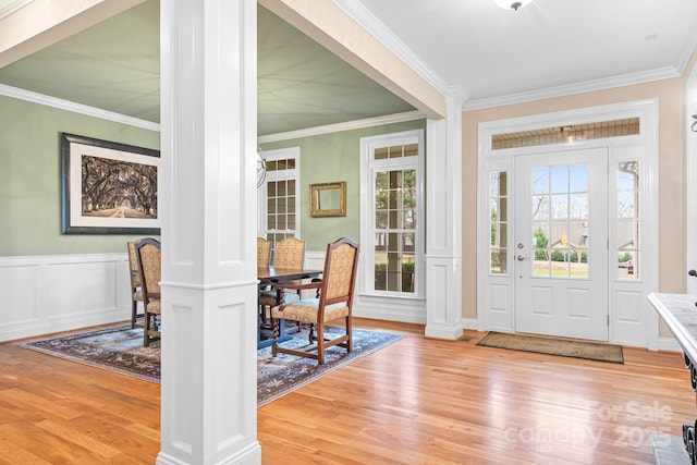 entryway with crown molding, decorative columns, and light hardwood / wood-style flooring