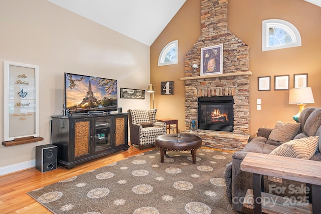 living room with wood-type flooring, a fireplace, and high vaulted ceiling