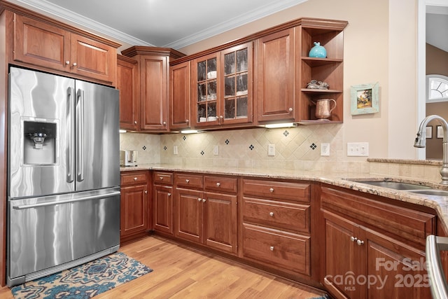 kitchen featuring stainless steel refrigerator with ice dispenser, sink, light stone counters, and decorative backsplash