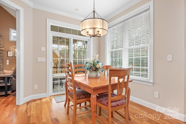 dining space with crown molding, an inviting chandelier, and light hardwood / wood-style floors