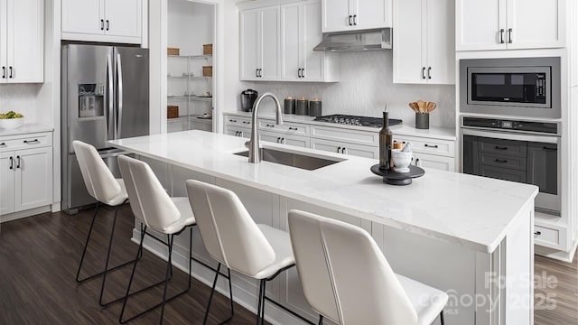 kitchen with a breakfast bar area, appliances with stainless steel finishes, a center island with sink, and sink