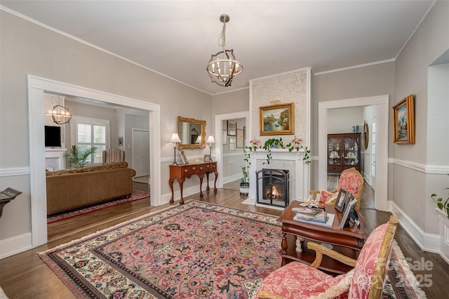 living room with crown molding, a large fireplace, hardwood / wood-style floors, and an inviting chandelier