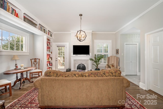 living room featuring wood-type flooring, a fireplace, a chandelier, and plenty of natural light