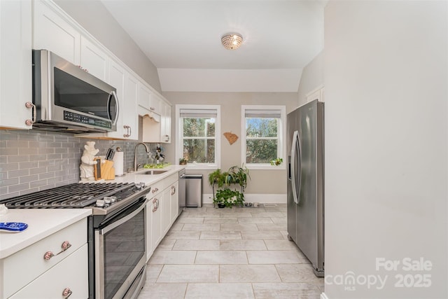 kitchen featuring lofted ceiling, sink, tasteful backsplash, white cabinetry, and stainless steel appliances