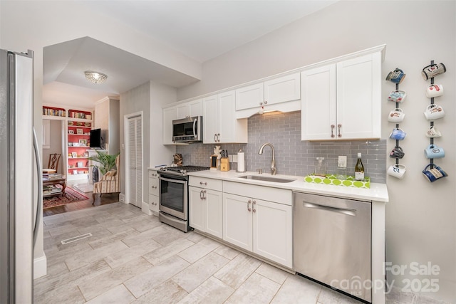 kitchen featuring stainless steel appliances, sink, white cabinets, and decorative backsplash