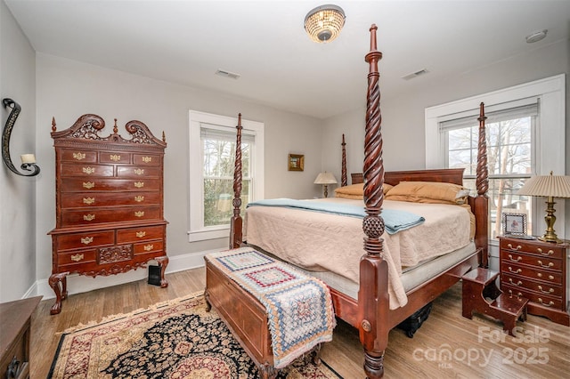 bedroom with multiple windows and light hardwood / wood-style flooring