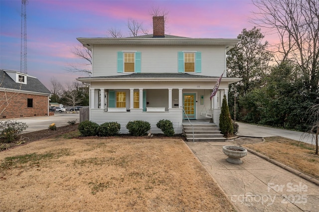 view of property with a yard, covered porch, and an outdoor fire pit