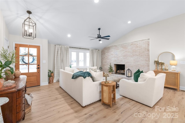 living room featuring lofted ceiling, a stone fireplace, ceiling fan, and light hardwood / wood-style flooring