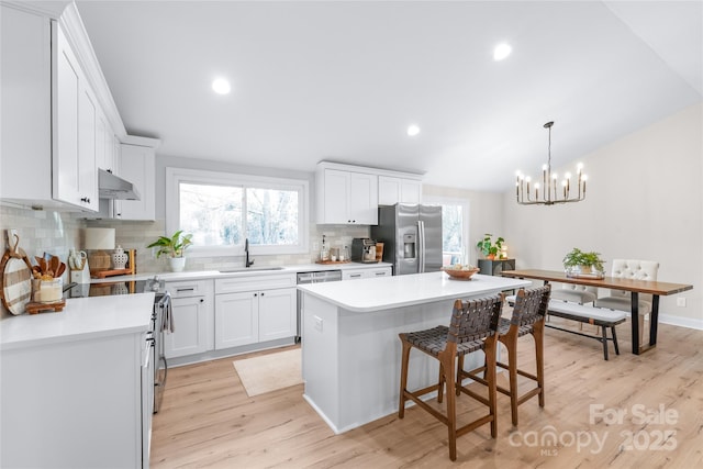 kitchen featuring sink, white cabinetry, stainless steel appliances, a center island, and light wood-type flooring