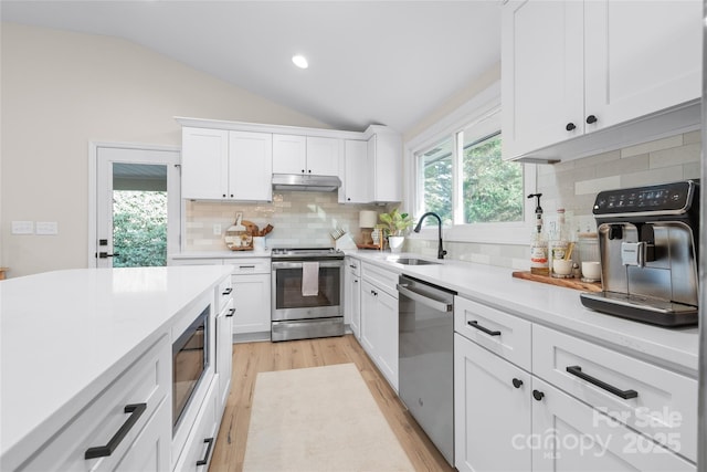 kitchen featuring lofted ceiling, appliances with stainless steel finishes, sink, and white cabinets