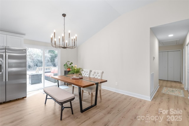 dining space with an inviting chandelier, lofted ceiling, and light hardwood / wood-style floors