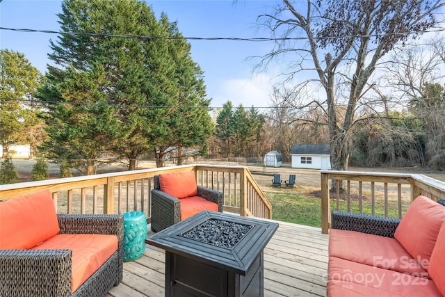 deck featuring a storage unit, a lawn, and a fire pit