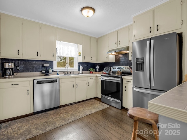 kitchen featuring dark hardwood / wood-style flooring, sink, cream cabinetry, and appliances with stainless steel finishes