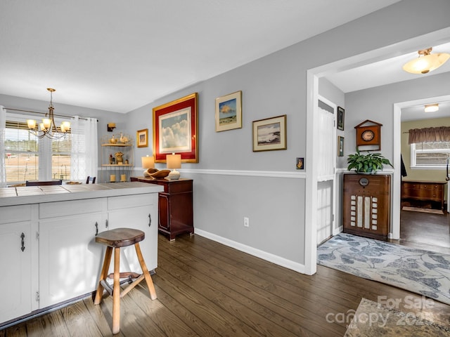 kitchen featuring dark wood-type flooring, a notable chandelier, white cabinets, decorative light fixtures, and tile countertops