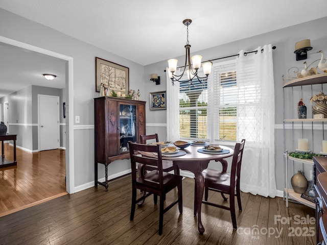 dining space with dark wood-type flooring and a notable chandelier