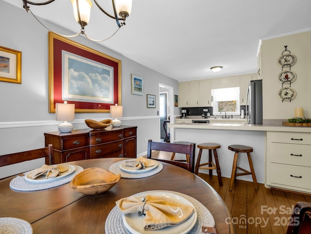 dining space with sink, a notable chandelier, and light wood-type flooring