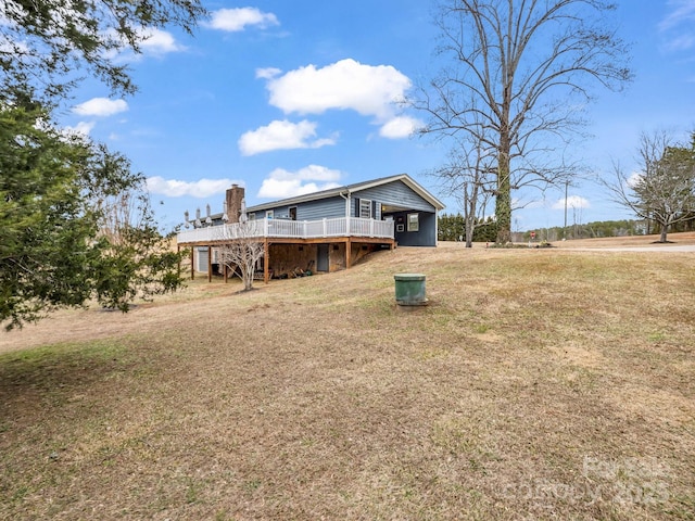 rear view of house featuring a lawn and a deck