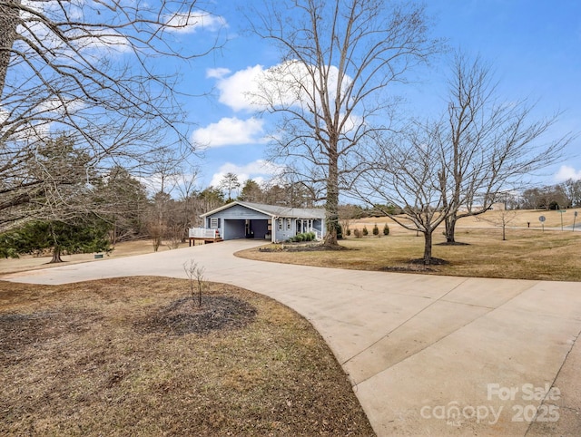 view of front of home with a garage, a front lawn, and a rural view