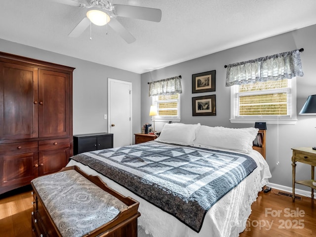 bedroom with hardwood / wood-style flooring, a textured ceiling, and ceiling fan