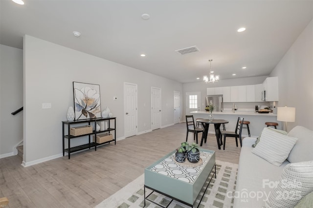 living room featuring a notable chandelier and light wood-type flooring