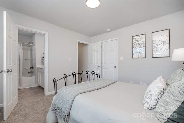 bedroom with connected bathroom and light colored carpet