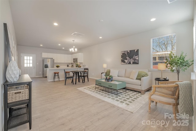 living room with an inviting chandelier and light hardwood / wood-style flooring