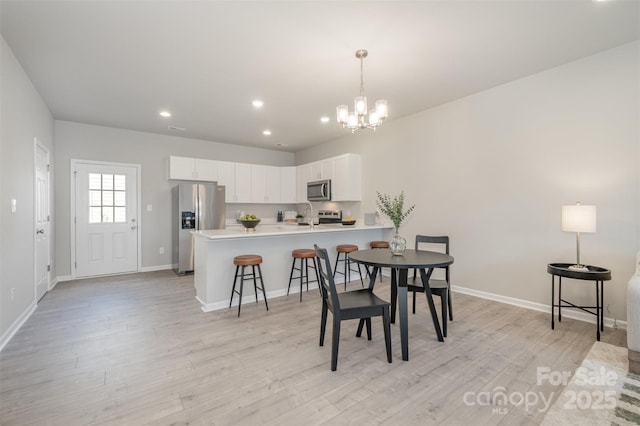 dining area with sink, a notable chandelier, and light hardwood / wood-style flooring