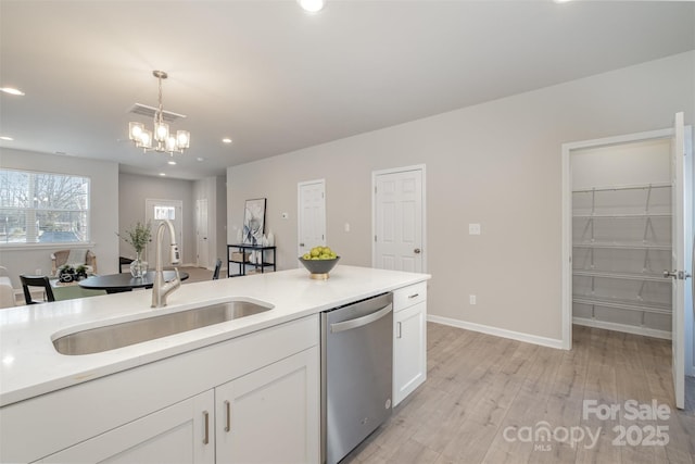 kitchen with sink, white cabinetry, stainless steel dishwasher, pendant lighting, and light hardwood / wood-style floors